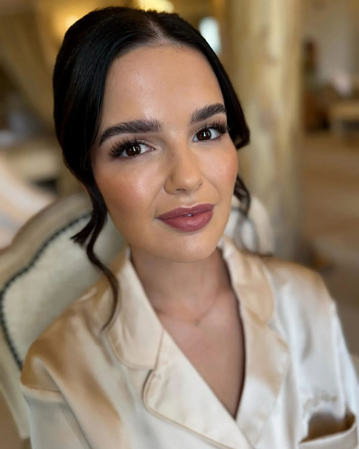 Dark-haired bride in a cream robe with a polished bridal eye