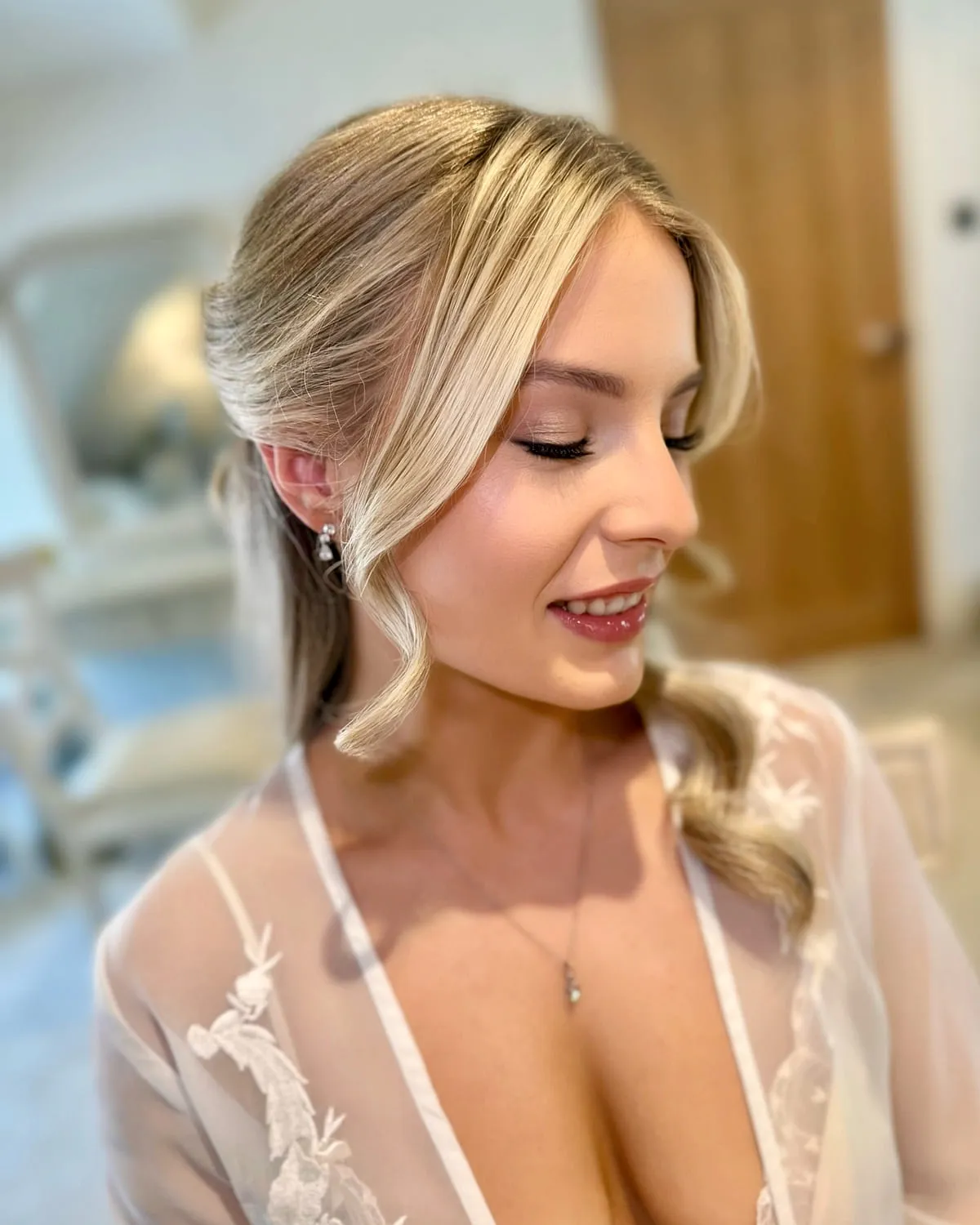 Bride in a lace bridal robe with a soft romantic eye and a low twisted updo
