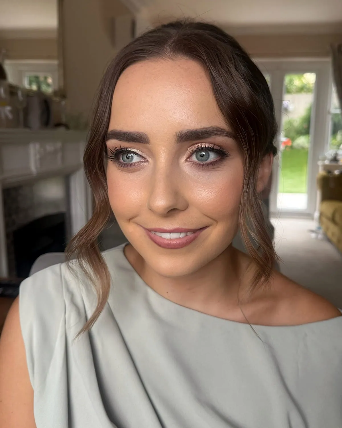 Bridal makeup with a soft smoky eye and glossy nude lip, worn with a sage off-shoulder dress