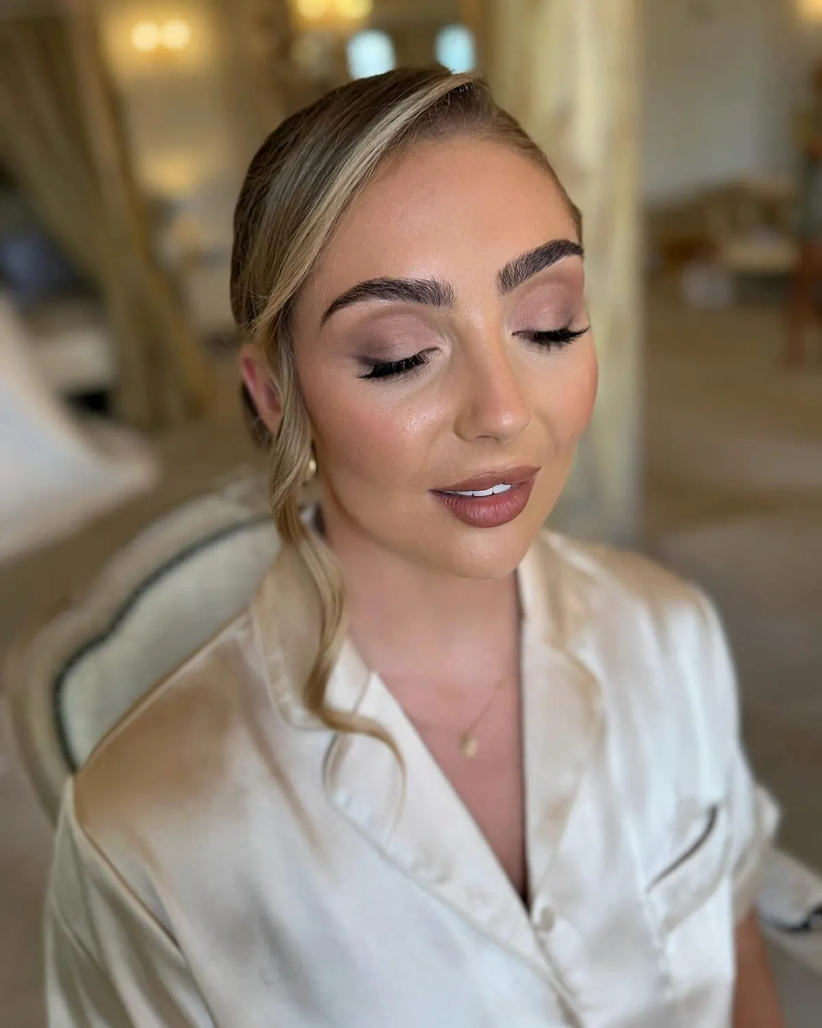 Bride in a satin robe with eyes closed, showing a blended neutral eye