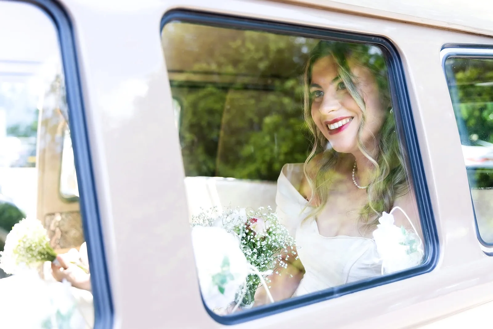 Bride photographed through the window of a vintage wedding car