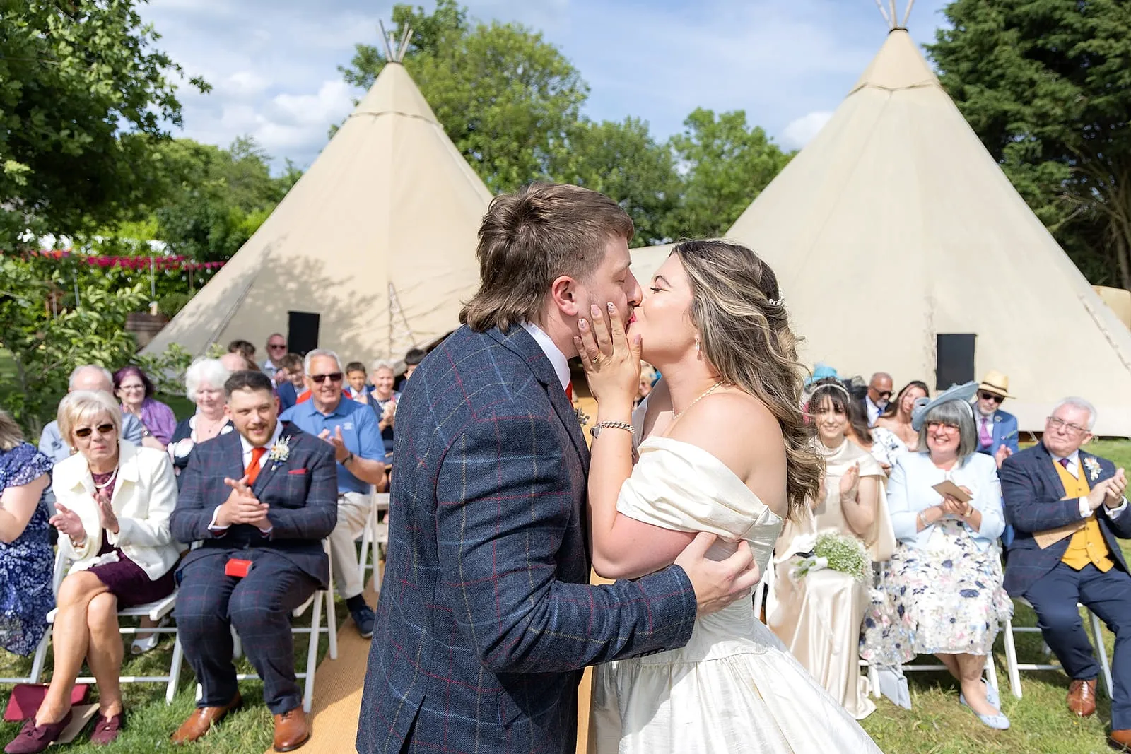 The first kiss during an outdoor tipi wedding ceremony