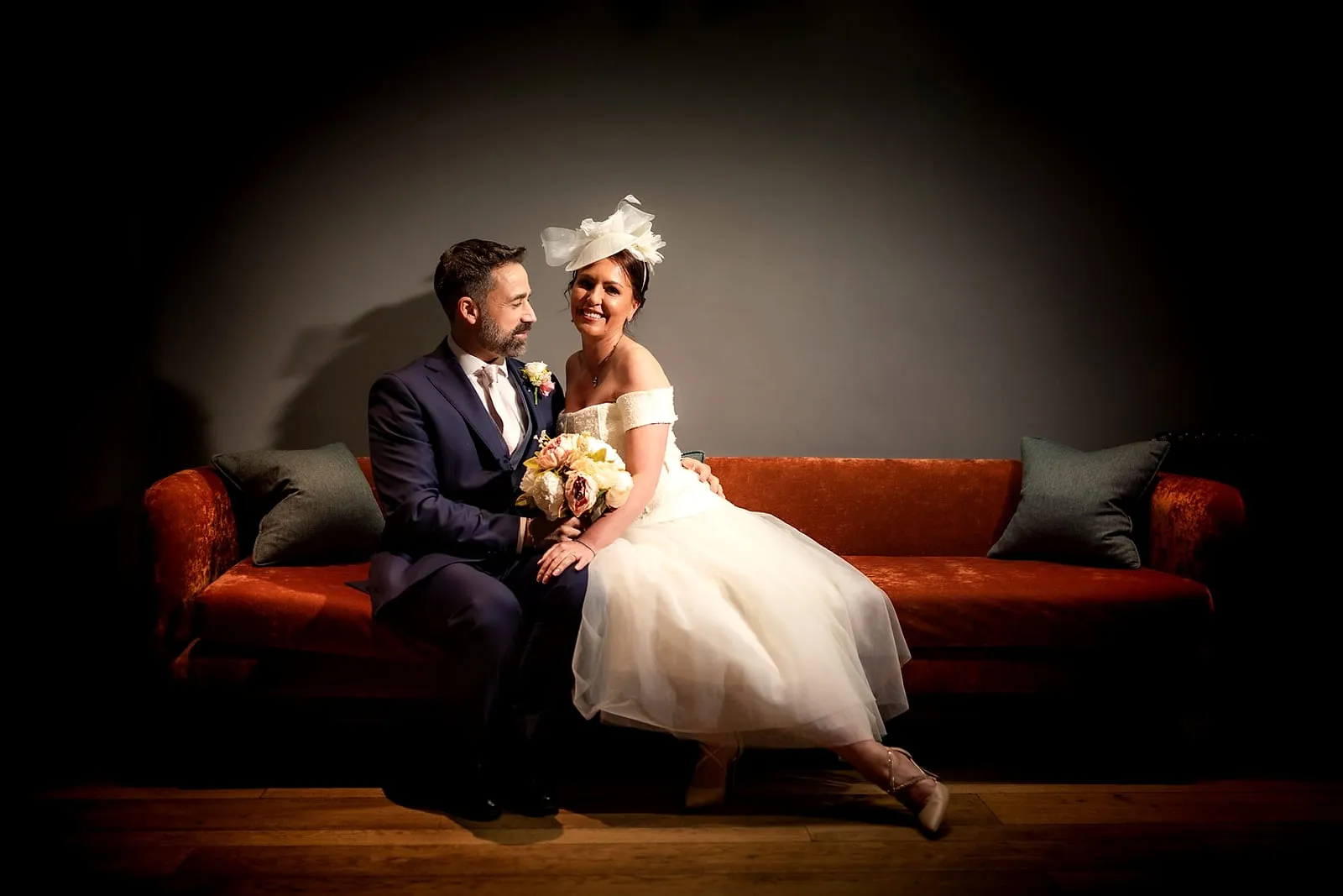 Bride and groom portrait on a red velvet sofa
