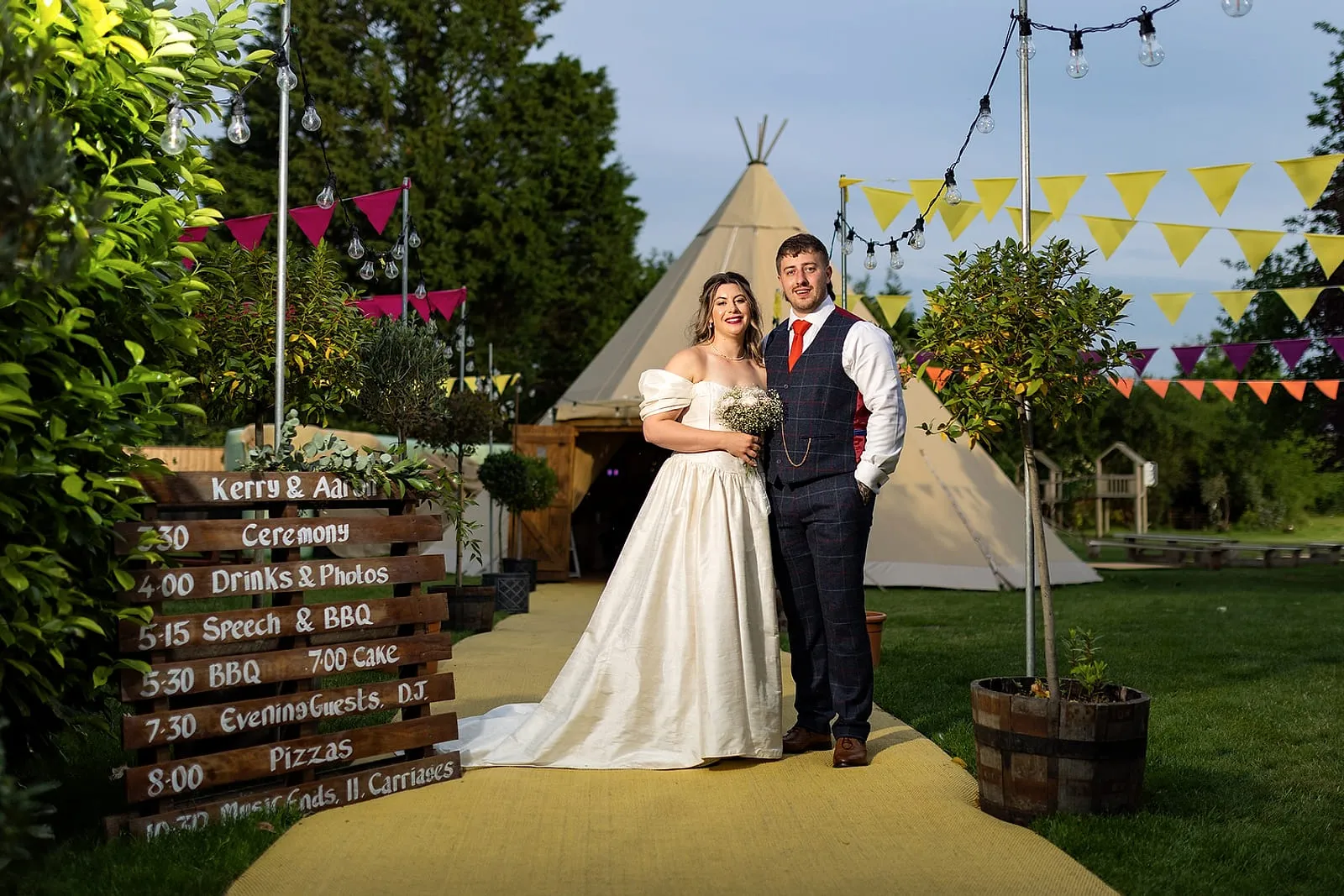 Bride and groom outside a tipi reception decorated with bunting